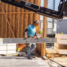 A construction worker with a blue shirt carrying some material