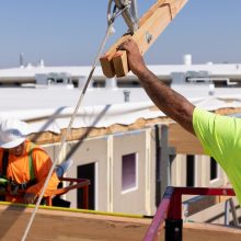 A man on a roof framing a building